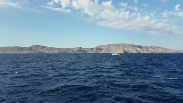 山を背に波の海に船を移動します。黒海の海岸とビーチの背景に. — ストック動画
