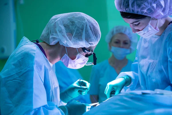 Chirurgien et son assistant pratiquant une chirurgie esthétique du nez dans la salle d'opération de l'hôpital. Restructuration du nez, augmentation. Rhinoplastie . — Photo