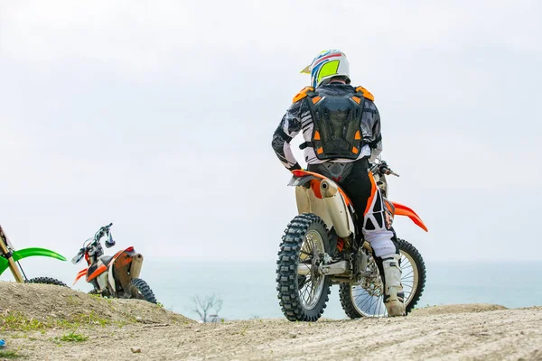 Motorcyklist i en skyddsdräkt som sitter på motorcykel framför havet — Stockfoto