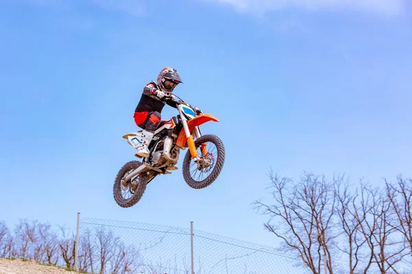 Corredor en una motocicleta en vuelo, salta y despega en un trampolín contra las montañas nevadas —  Fotos de Stock