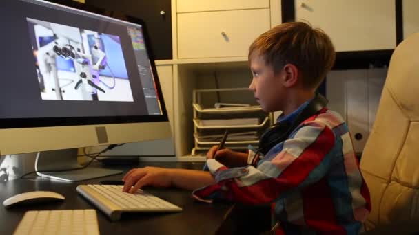 Chytrý chlapec pracuje na projektu pro svůj počítač. Chlapce pracuje na počítači pomocí grafického tabletu — Stock video