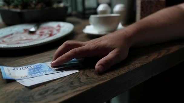 Man betaalt cash voor bill in café. Papiergeld bankbiljetten in mans hand met restaurant check op de houten tafel. — Stockvideo