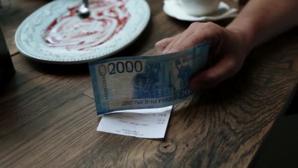 Man betaalt cash voor bill in café. Papiergeld bankbiljetten in mans hand met restaurant check op de houten tafel. — Stockvideo