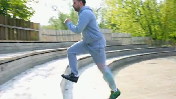 El hombre corre hacia abajo y luego sube un conjunto de escaleras en el parque. hombre corriendo las escaleras en el parque . — Vídeo de stock