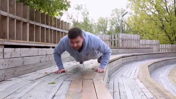 Muž cvičit svaly paže venkovní. Muž dělá push up cvičení v létě parku — Stock video
