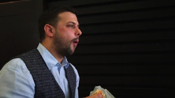 Primer plano retrato del hombre barbudo comiendo sándwich. Imágenes de vídeo HD completas en tiempo real. Comida rápida. Vista lateral — Vídeos de Stock