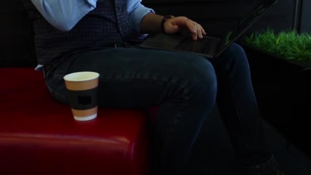 Фрилансер-бизнесмен работает на ноутбуке с диаграммами на экране в кафе, пьет кофе и разговаривает по телефону. Отслеживание и выявление выстрела — стоковое видео