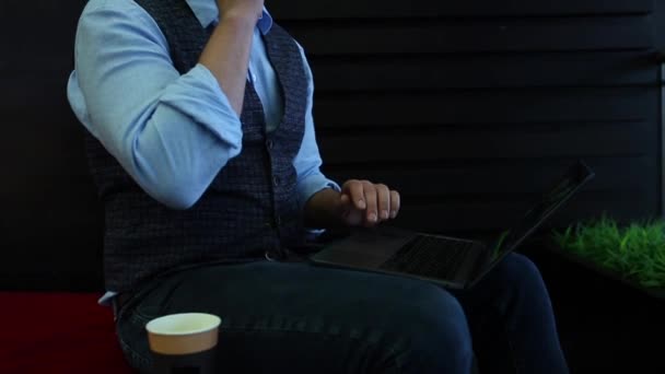 Фрілансер бізнесмен працює на ноутбуці з діаграмами на екрані в кафе, п'є каву і розмовляє по телефону. Відстеження і виявлення пострілу — стокове відео