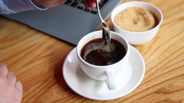 Крупным планом мужчины вручную наливают сахар в чашку кофе в баре и помешивают его — стоковое видео