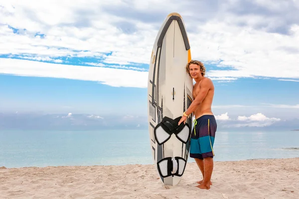 Stattliche Mann zu Fuß mit weißen blanken Surfbrett warten auf Welle zu surfen Spot am Meer Ozeanküste. Konzept von Sport, Fitness, Freiheit, Glück, neues modernes Leben, Hipster. — Stockfoto