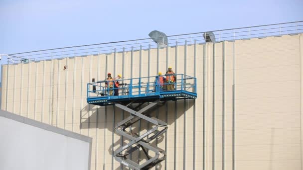 Rampicanti industriali fissati nel cestello di sicurezza riparano la facciata dell'edificio . — Video Stock