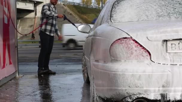 Man tvättar sin bil med vattendimma från högtryckstvätt. Biltvätt självbetjäning. — Stockvideo