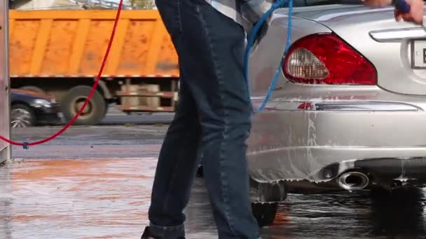 Człowiek, mycia samochodu, jego rozpyloną wodą z wysokociśnieniowej. Myjnia samoobsługowa. — Wideo stockowe
