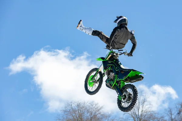 Racer na motocyklu w locie, skacze i startuje na springboard przeciwko snowy góry — Zdjęcie stockowe