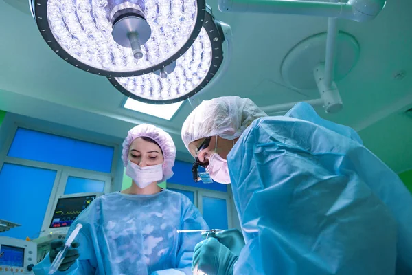 Chirurgien et son assistant pratiquant une chirurgie esthétique du nez dans la salle d'opération de l'hôpital. Restructuration du nez, augmentation. Rhinoplastie . — Photo