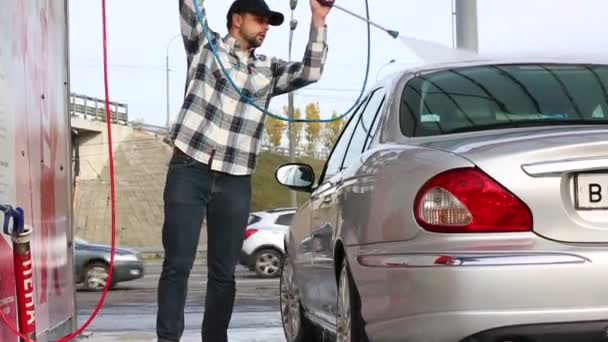 Ο άνθρωπος πλύσιμο του αυτοκινήτου με ψεκασμό με νερό από το μηχάνημα πλύσης υψηλής πίεσης. Car wash, self service. — Αρχείο Βίντεο