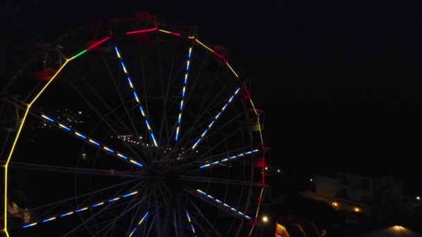 Vergnügungspark Luftaufnahmen Nacht Stadt Lichter. Clip. Luftaufnahme, die sich vor einem schönen Riesenrad im Hintergrund bewegt, das die Sommernacht erhellt — Stockvideo