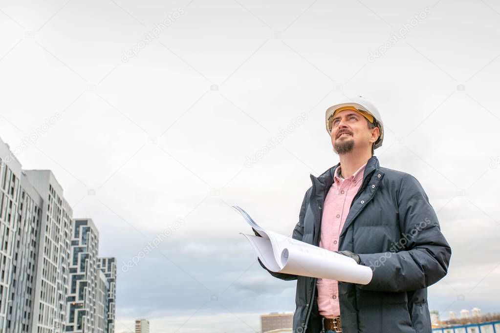 Portrait of architect at work with helmet in a construction site,reads the plan.