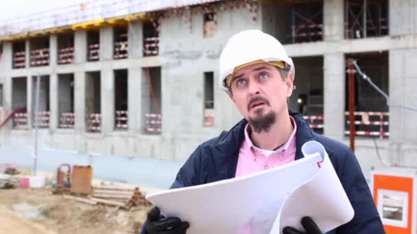 Stavební inženýr nebo architekt v přilbě s plánem výstavby na staveništi. — Stock video