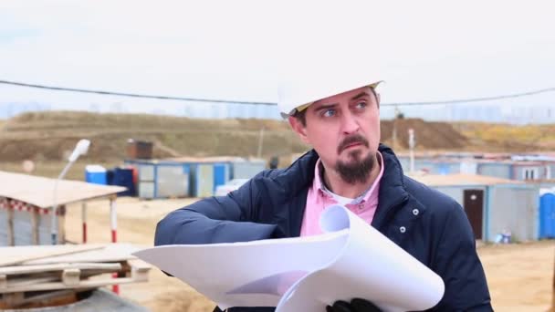 Ingenieur bouwkunde of architect in helm met een plan van de bouw op de bouwplaats. — Stockvideo
