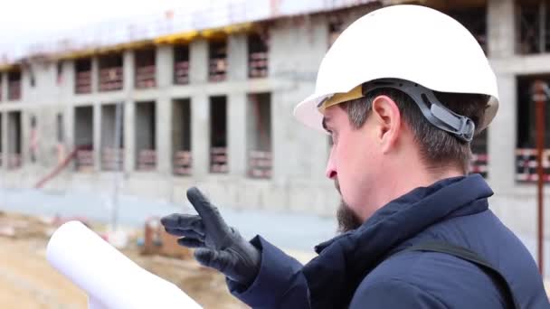 Stavební inženýr nebo architekt v přilbě s plánem výstavby na staveništi. — Stock video