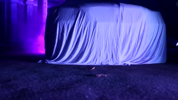 Carro coberto por tecido na fumaça em pé na casa abandonada iluminado em roxo . — Vídeo de Stock