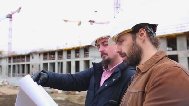 Zwei Ingenieure sprechen über das Projekt für das Bauwerk. Sie betrachten beide Papierprojekte — Stockvideo