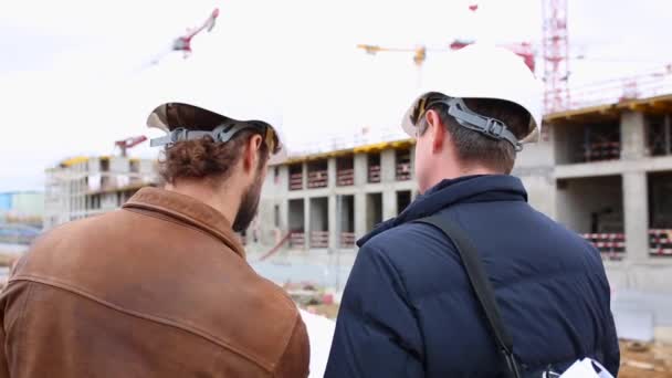 Deux ingénieurs parlent du projet du bâtiment de construction. Ils examinent les deux projets de papier — Video