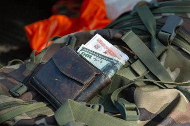 Corruption concept. Money of different countries in a wallet placed on a military uniform clipart
