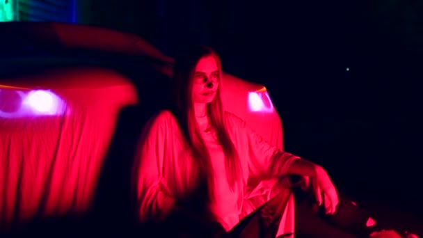 Vrouw met dode bruid make-up voor Halloween staande door de auto in de jurk wit bruid in het donker bij verlaten huis — Stockvideo
