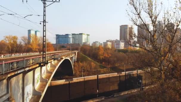 Aerial shot of tall bridge crossing river. Drone flies under the bridge against the autumn landscap — Stock Video