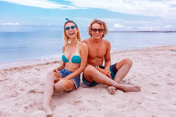 Retrato de pareja joven enamorada en la playa y disfrutando del tiempo juntos. Pareja joven divirtiéndose en una costa arenosa . — Foto de Stock