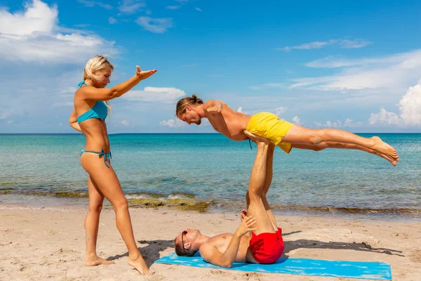 Dwa młody mężczyzna i kobieta na plaży robi fitness joga ćwiczenia razem. Element Acroyoga dla siły i równowagi — Zdjęcie stockowe