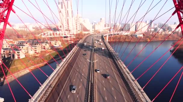 Flygfoto över pittoreska bro som korsar floden Moskva i Moskva. Bilar trafik på snedkabelbro av röd färg på dagtid. — Stockvideo