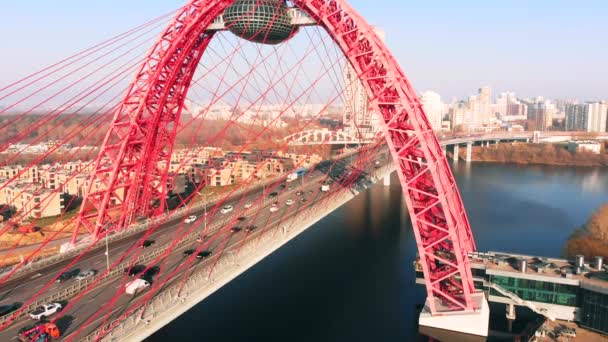 Пташиного польоту Picturesque міст, що перетинає річку Москву в Москві. Рух автомобілів на вантовий міст червоного кольору в денний час. — стокове відео