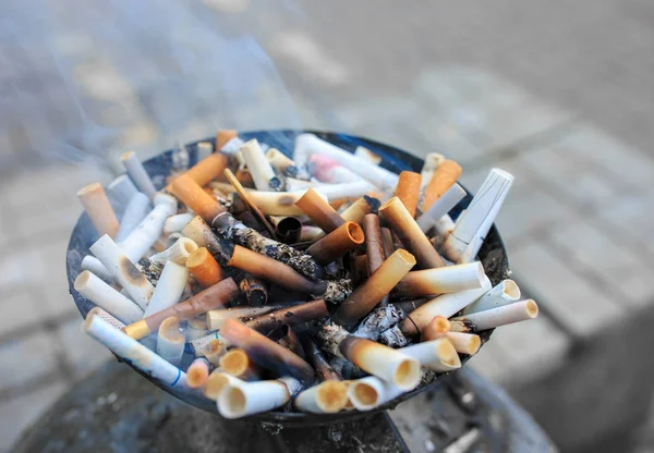 Rabos de cigarro no cinzeiro. Close up monte de muitos fumar cigarros stubs, beatas de cigarro em cinzeiro — Fotografia de Stock