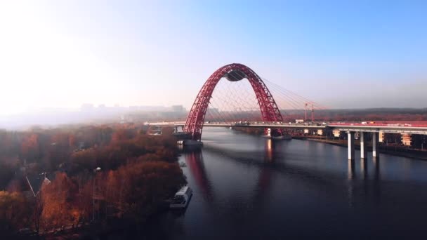 Пташиного польоту Picturesque міст, що перетинає річку Москву в Москві. Рух автомобілів на вантовий міст червоного кольору в денний час. — стокове відео