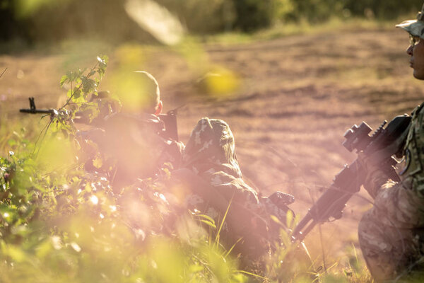 Sniper team armed with large caliber, sniper rifle, shooting enemy targets on range from shelter, sitting in ambush