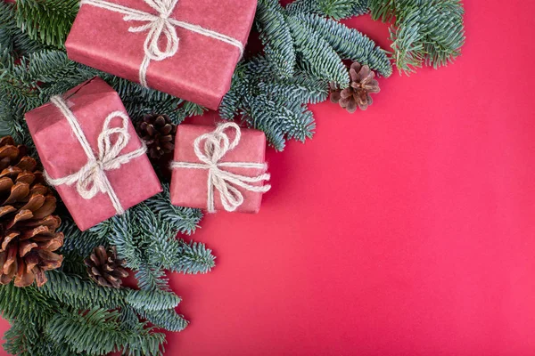 Composición navideña. Decoraciones rojas de Navidad, ramas de abeto con cajas de regalo de juguetes sobre fondo rojo. Plano, vista superior, espacio para copiar — Foto de Stock