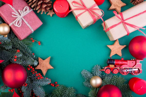 Christmas composition. Christmas green decorations, fir tree branches with toys gift boxes on green background. Flat lay, top view, copy space