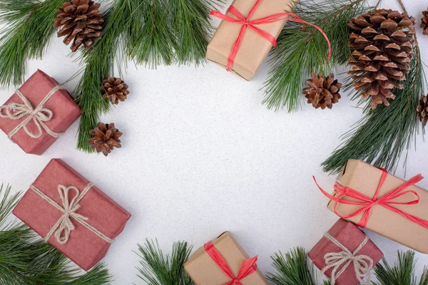 Composición navideña. Decoraciones blancas navideñas, ramas de abeto con cajas de regalo de juguetes sobre fondo blanco. Plancha plana, vista superior, espacio para copiar, tarjeta de felicitación — Foto de Stock