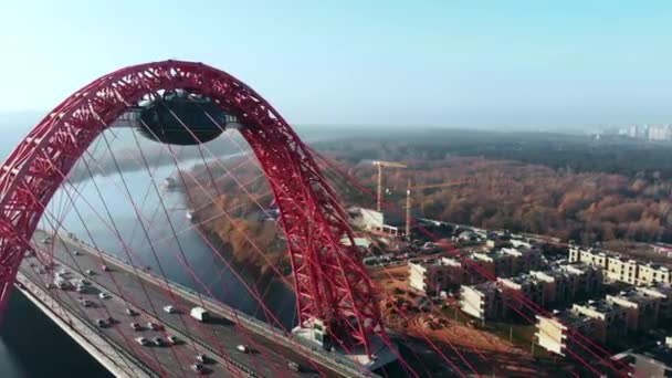 Flygfoto över den ikoniska landmärke som är pittoreskt bro som korsar floden Moskva i Moskva. Bilar trafik på snedkabelbro av röd färg på dagtid. 4k. — Stockvideo