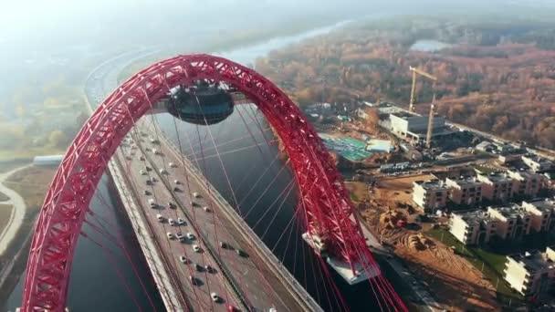 Moskova'da Moskova Nehri geçerek Picturesque köprü ikonik simgesel yapı hava görünümünü. Gün zaman kırmızı renk askılı köprüde araba trafik. 4k. — Stok video