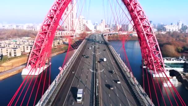 Flygfoto över den ikoniska landmärke som är pittoreskt bro som korsar floden Moskva i Moskva. Bilar trafik på snedkabelbro av röd färg på dagtid. 4k. — Stockvideo