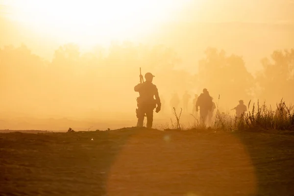 Silhouette action soldats marchant tenir armes l'arrière-plan est fumée et coucher de soleil et équilibre des blancs navire effet style art sombre — Photo