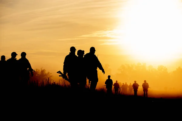 Silhouette action soldats marchant tenir armes l'arrière-plan est fumée et coucher de soleil et équilibre des blancs navire effet style art sombre — Photo