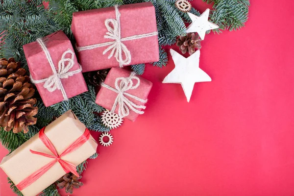 Composición navideña. Decoraciones rojas de Navidad, ramas de abeto con cajas de regalo de juguetes sobre fondo rojo. Plano, vista superior, espacio para copiar — Foto de Stock