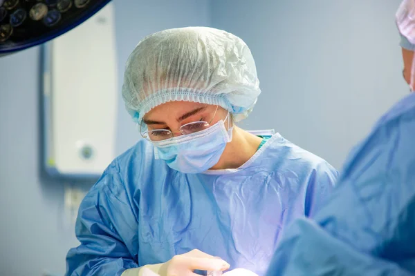 Médico femenino en quirófano. Cirujano médico en trabajo protector usar guantes, máscara y gorra — Foto de Stock