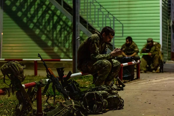 Vue de côté soldat sérieux écrivant message au téléphone tout en portant en uniforme et entouré d'armes. Technologie et concept militaire — Photo