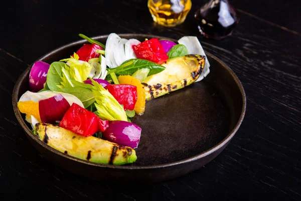 Köstliche warme gegrillte Gemüsesalat mit Avocado im Restaurant Hintergrund. gesundes exklusives Essen auf großer schwarzer Platte in Nahaufnahme — Stockfoto
